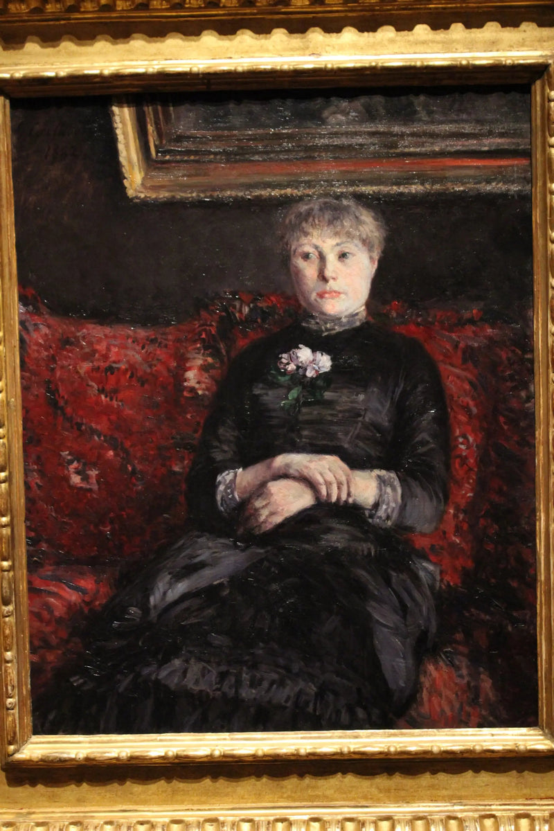 Femme assise sur un canapé à fleurs rouges - Gustave Caillebotte
